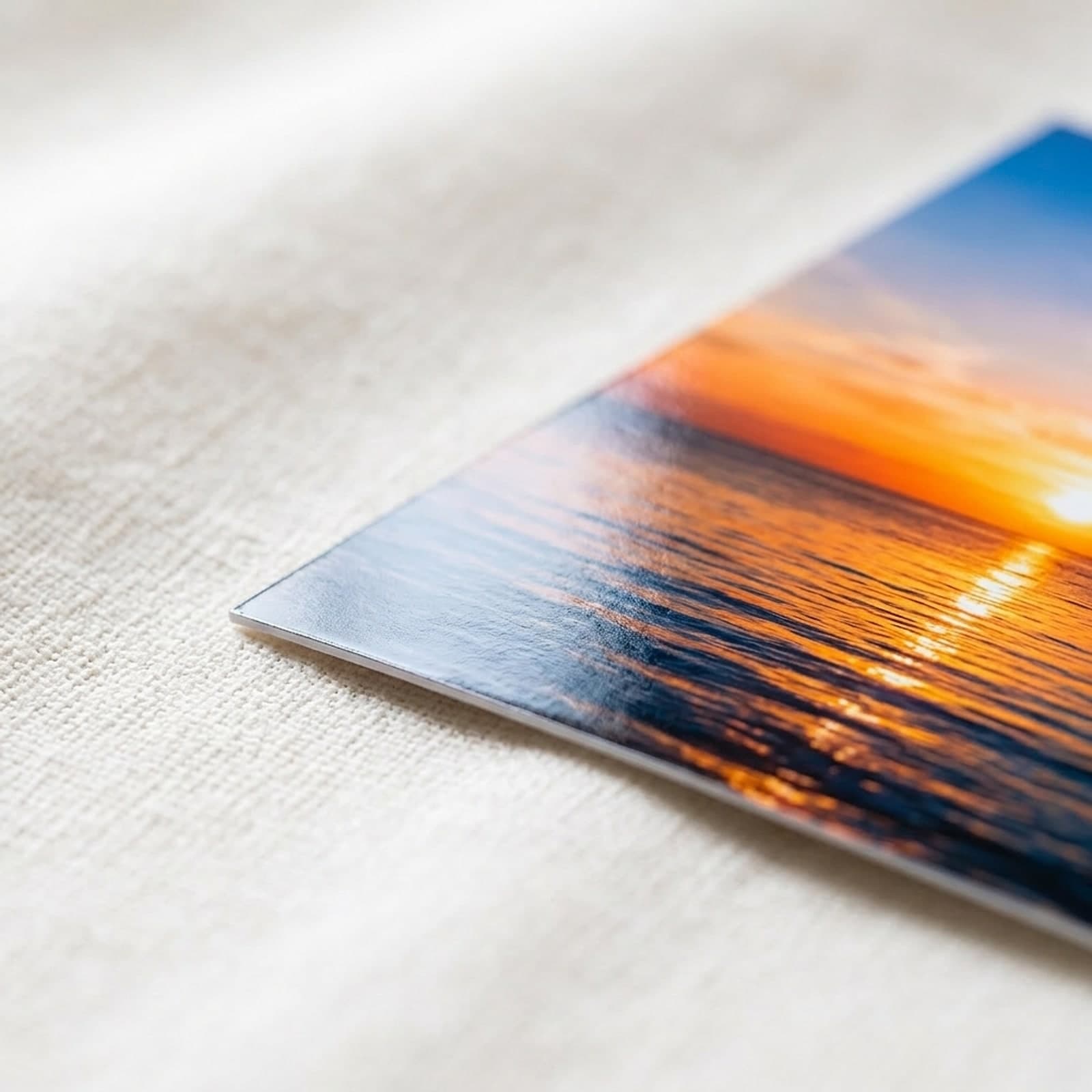 Extreme close-up of the glossy corner of a sunset photo print resting on white linen